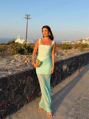 Woman in a light blue dress standing on a stone path with a scenic background
