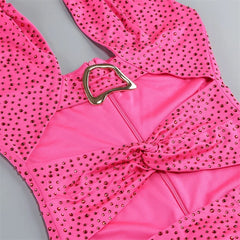 Pink swimsuit with gold embellishments on a gray background