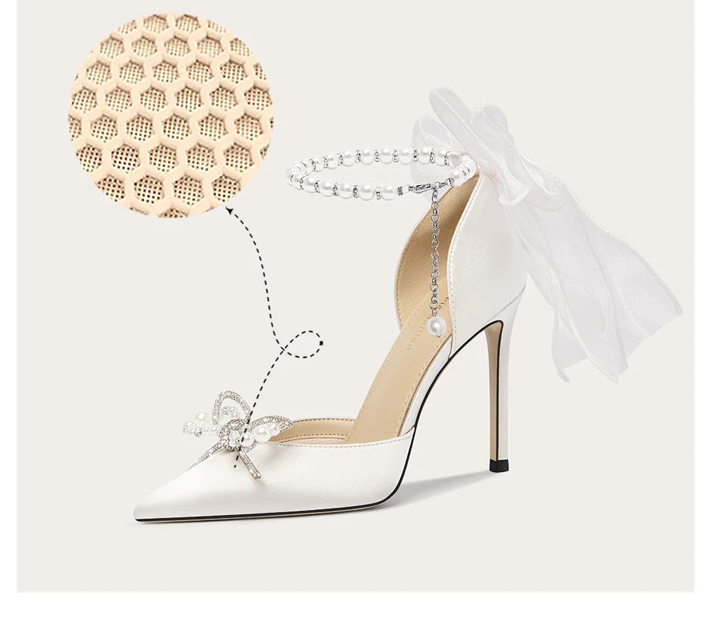 White high-heeled shoe with decorative bow and sheer ribbon on a light background