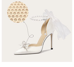 White high-heeled shoe with decorative bow and sheer ribbon on a light background