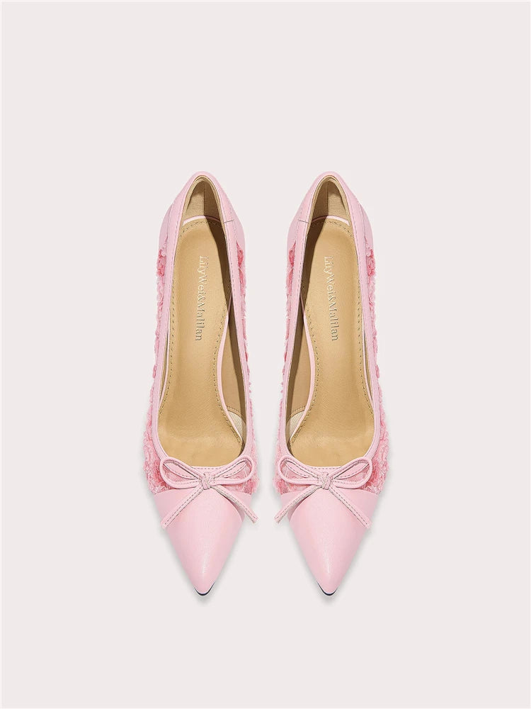 Pair of pink high-heeled shoes with bow details on a light gray background