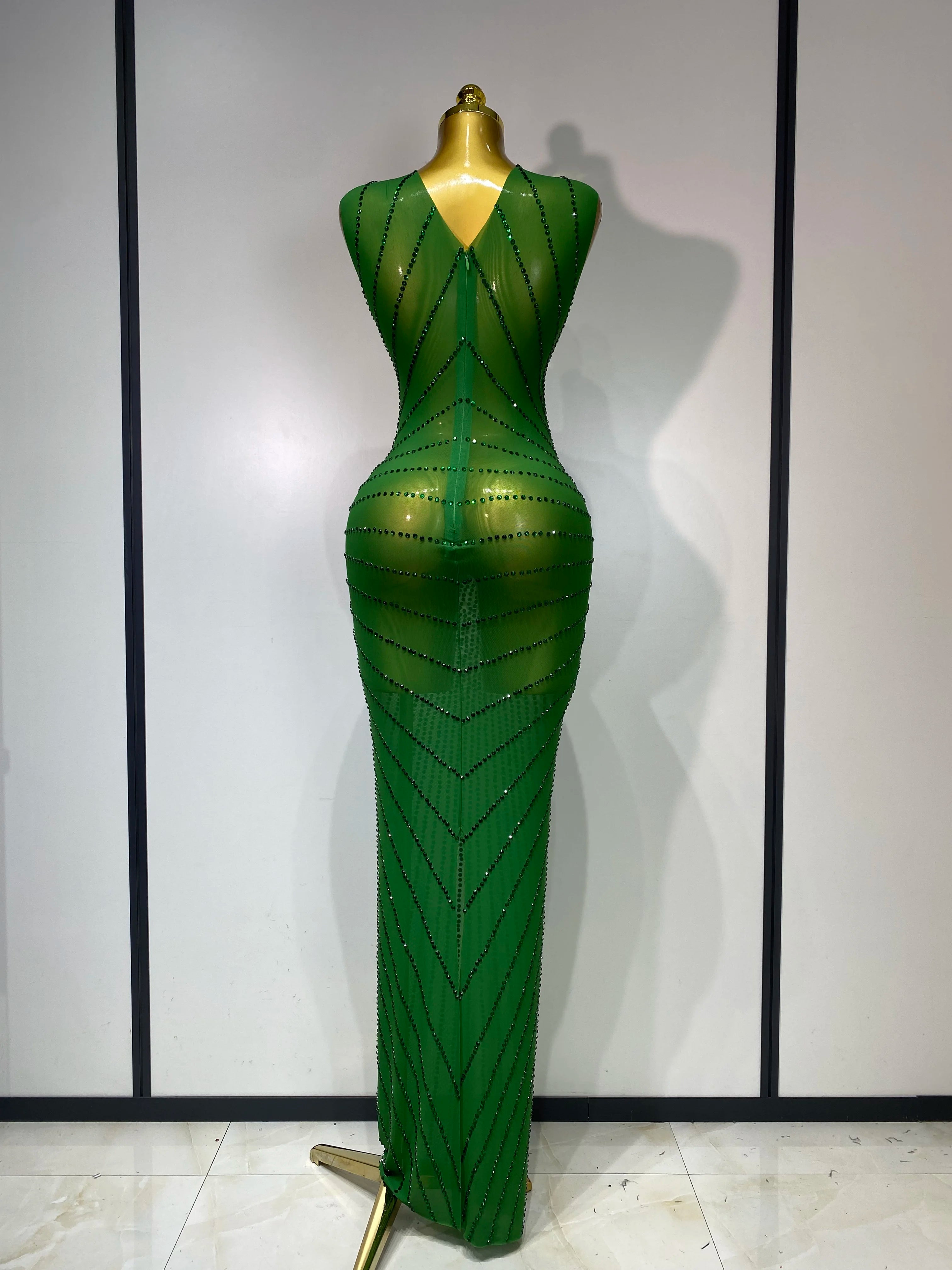Green evening gown on a mannequin against a plain background