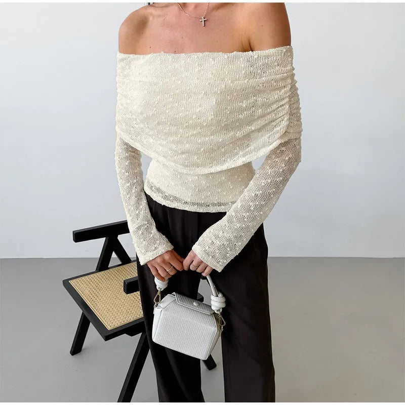 Person wearing a white off-shoulder top holding a white handbag against a plain background