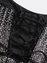 Black swimsuit with ruffled details and sparkling embellishments on a white background
