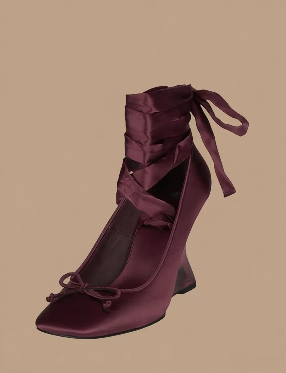 Maroon high-heeled shoe with ribbon detailing on a beige background