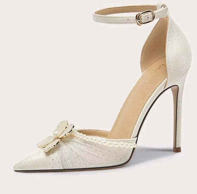 White high-heeled shoe with decorative bow and pearls on a white background