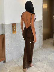 Woman wearing a brown open-back dress in an elevator shaft.