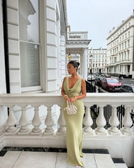 Woman in a green dress standing on a balcony with a city street in the background