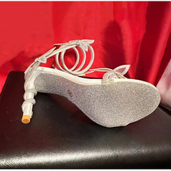 Silver glitter high-heeled shoe on a red fabric background