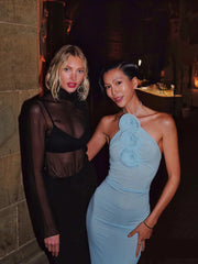 Two women posing together in formal attire indoors.