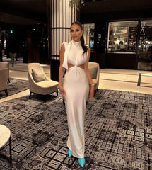 Woman in a white dress standing in a stylishly decorated room with patterned carpet and modern furniture.