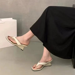 Wedge flip-flop sandal in white on a floor