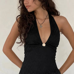 Woman wearing a black dress with a floral detail on a plain background