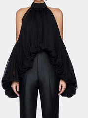 Black halter top with sheer sleeves and black pants on a white background