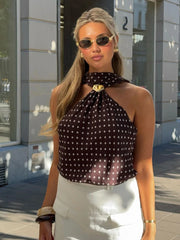 Woman wearing a polka dot top and sunglasses outdoors.