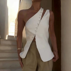 Person wearing a white one-shoulder top with button details outdoors.