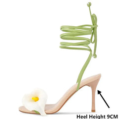 High-heeled sandal with green laces and a calla lily design on a white background