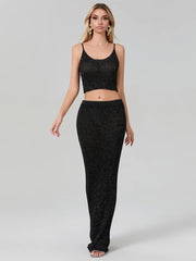 Woman wearing a black sparkly top and pants on a gray background