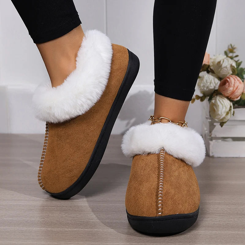 Brown slippers with white fur trim worn indoors on a wooden floor.