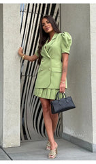Woman in a green outfit standing against a modern architectural background