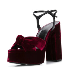 Side profile of a black suede platform slingback heel with knot detail.