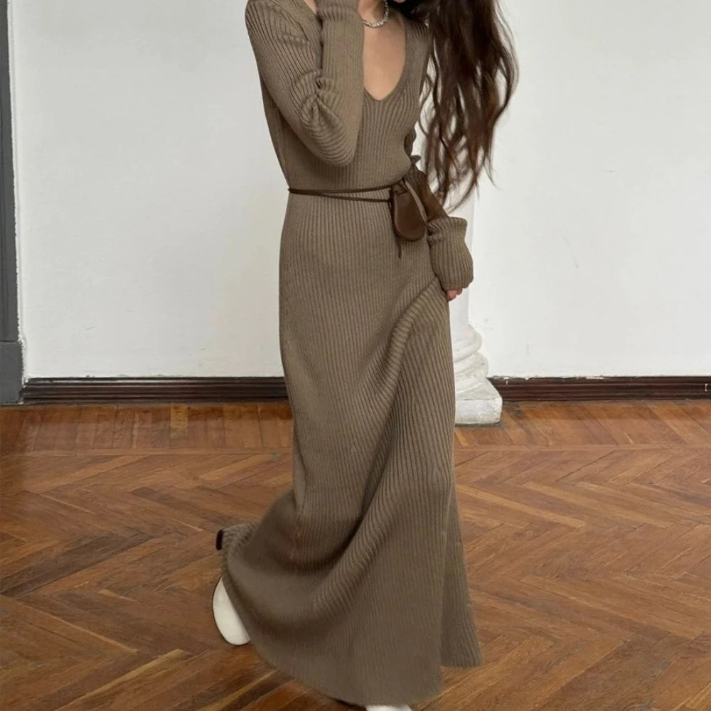 Person wearing a long brown ribbed dress on a wooden floor.