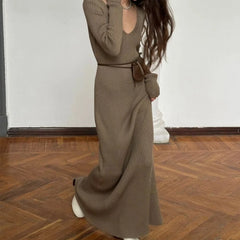 Person wearing a long brown ribbed dress on a wooden floor.