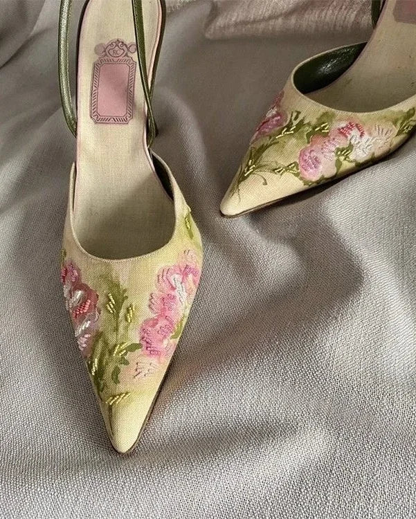 Pair of floral high-heeled shoes on a light fabric background