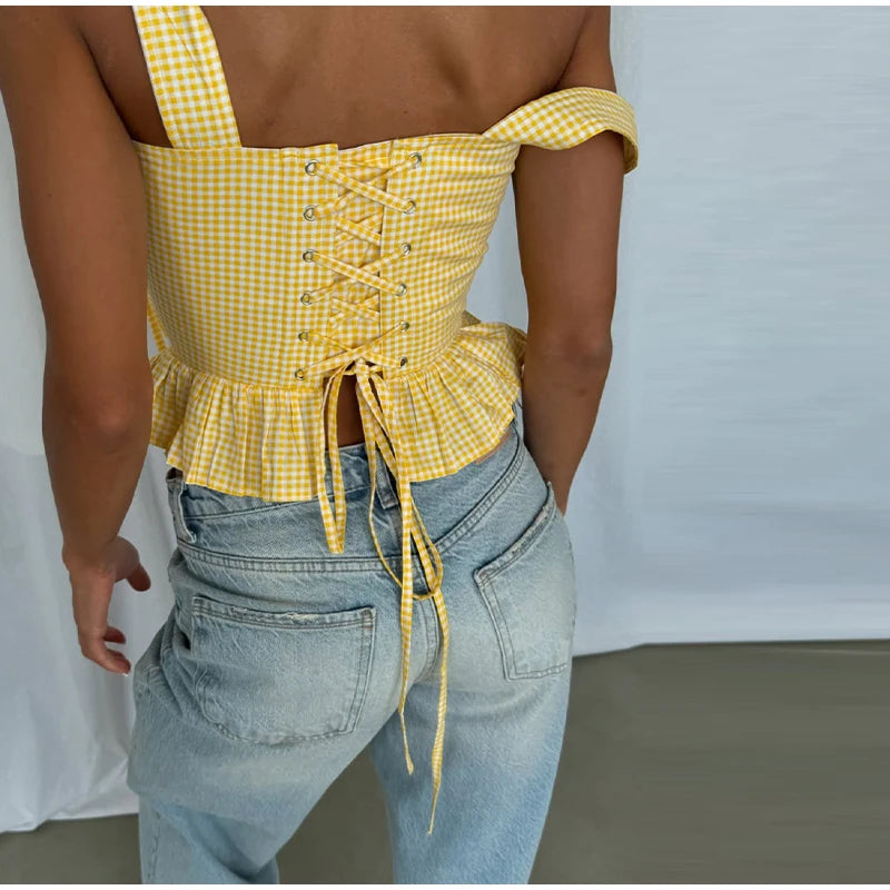 Person wearing a yellow checkered top and blue jeans against a plain background