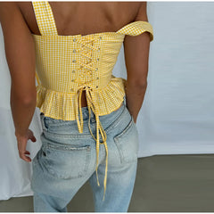 Person wearing a yellow checkered top and blue jeans against a plain background