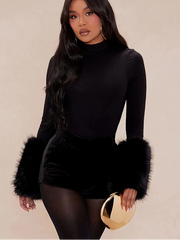 Woman wearing a black outfit with fur accents on a beige background