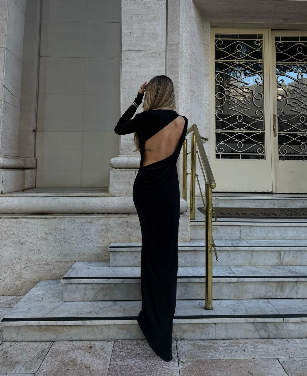 Woman in a black dress standing on steps of a classical building