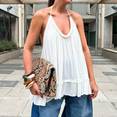 Person wearing a white halter top and blue jeans, holding a patterned clutch.