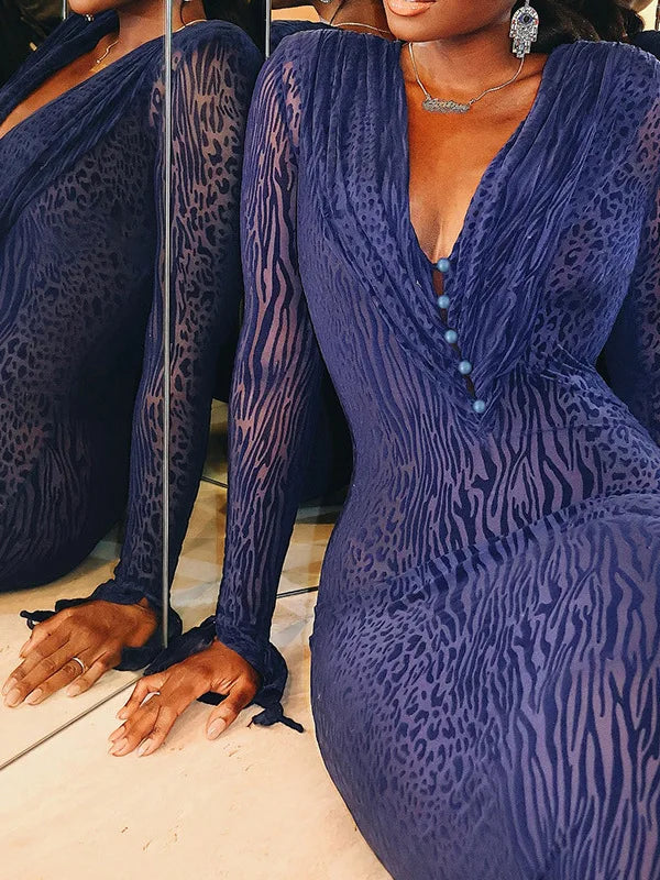 Woman wearing a blue patterned dress with long sleeves and a deep neckline.
