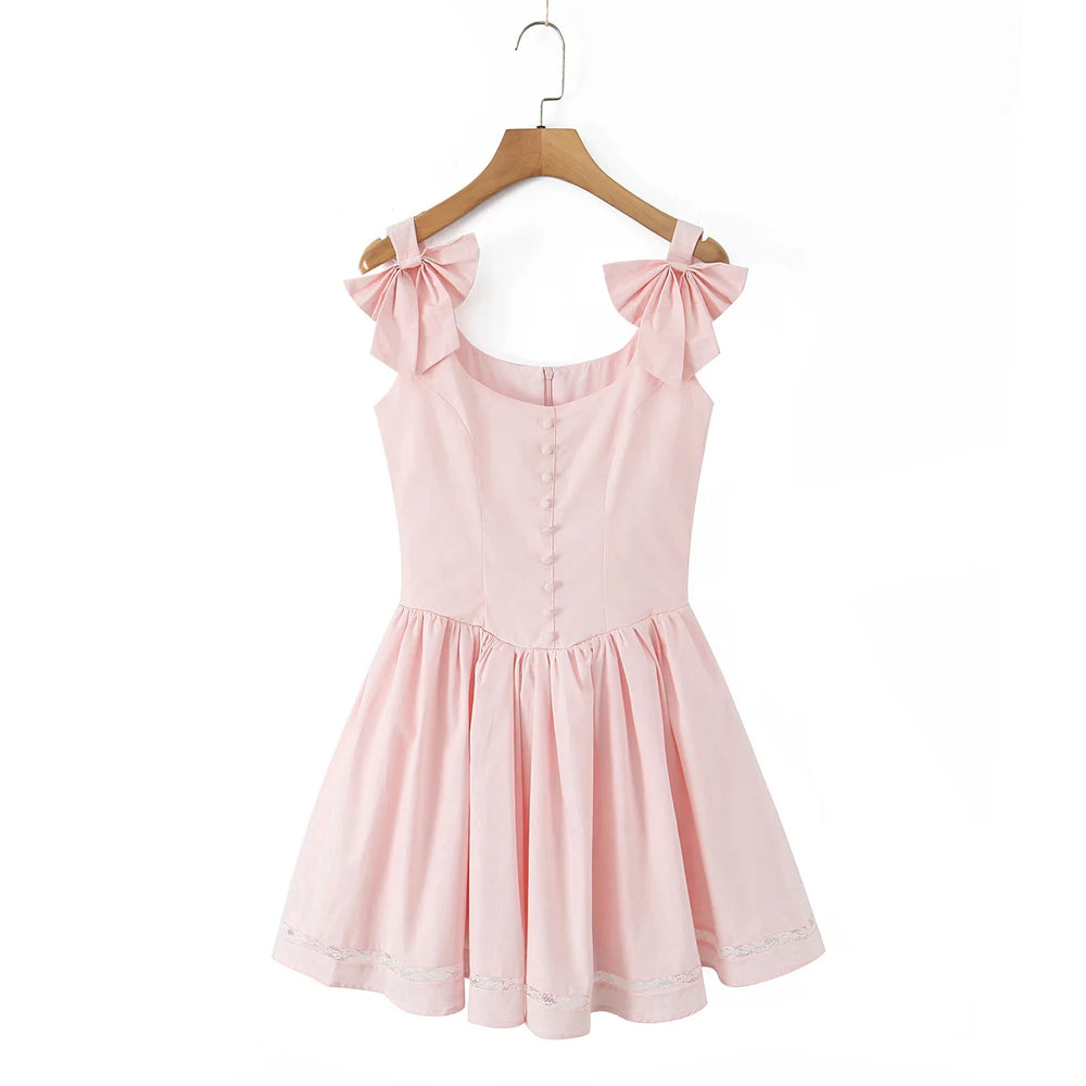Pink dress with bow straps on a hanger against a white background