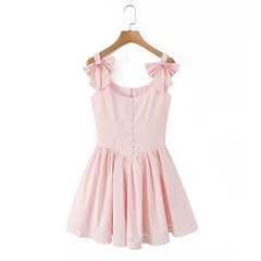 Pink dress with bow straps on a hanger against a white background