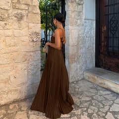 Woman in a brown dress standing in front of a stone wall and door.