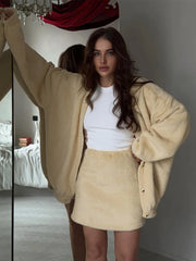 Woman wearing a beige cardigan and skirt in a bedroom setting