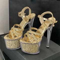 Gold glitter high-heeled shoes on a black surface with a dark background