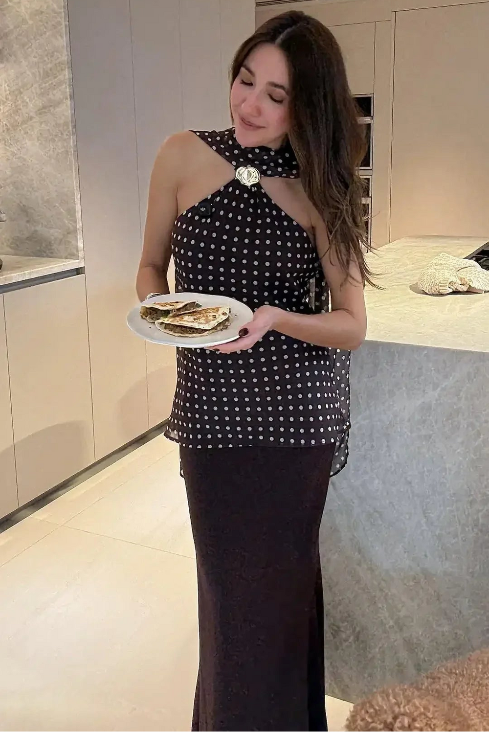 Woman holding a plate of food in a modern kitchen