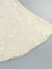 White fabric with floral embroidery on a gray background
