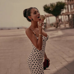 Woman in a polka dot dress eating ice cream outdoors.