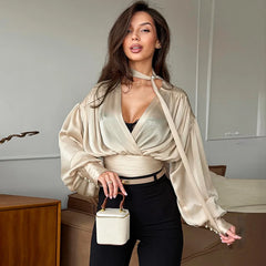 Woman in a stylish outfit holding a white handbag indoors.