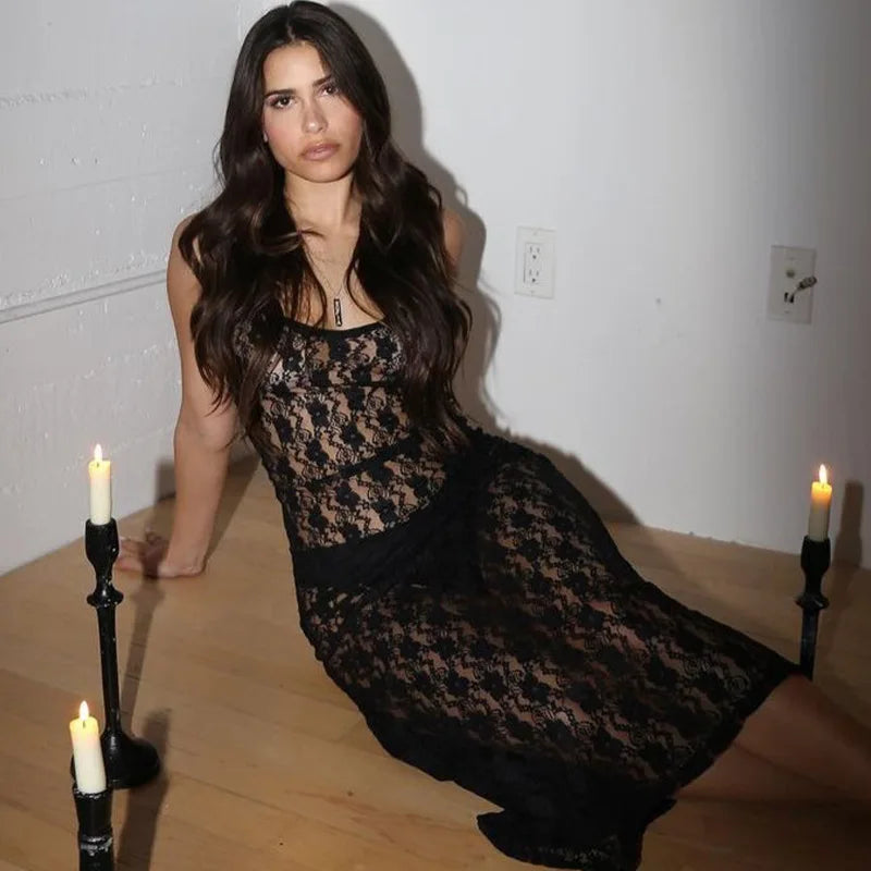Woman in a black lace dress sitting on the floor with candles around her.