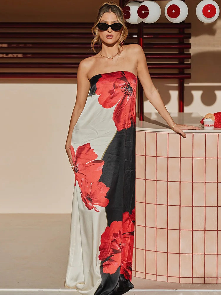 Woman in a strapless dress with red and black floral patterns standing indoors.