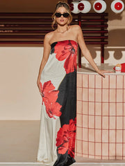 Woman in a strapless dress with red and black floral patterns standing indoors.