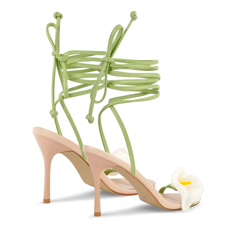 High-heeled shoes with green straps and a white flower on a white background