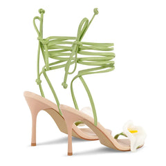 High-heeled shoes with green straps and a white flower on a white background