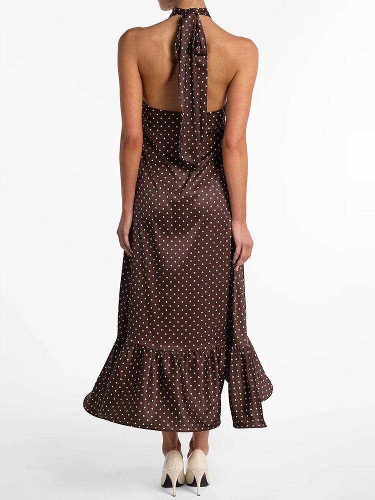 Woman wearing a brown polka dot halter neck dress on a white background
