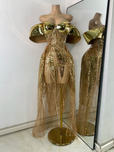 Gold sequin dress on a mannequin with a mirror reflection against a white wall.